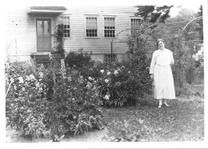 SA0064 - Alice Smith was from the Church Family. She is shown in a garden, an unidentified building in the background. Identical photos.